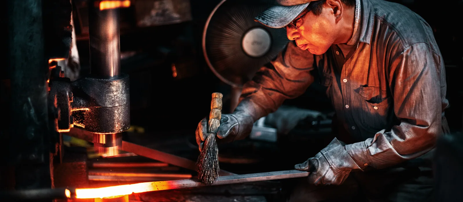 Craftsman forging a Sakai Takayuki knife amid sparks at the Aoki Hamono workshop